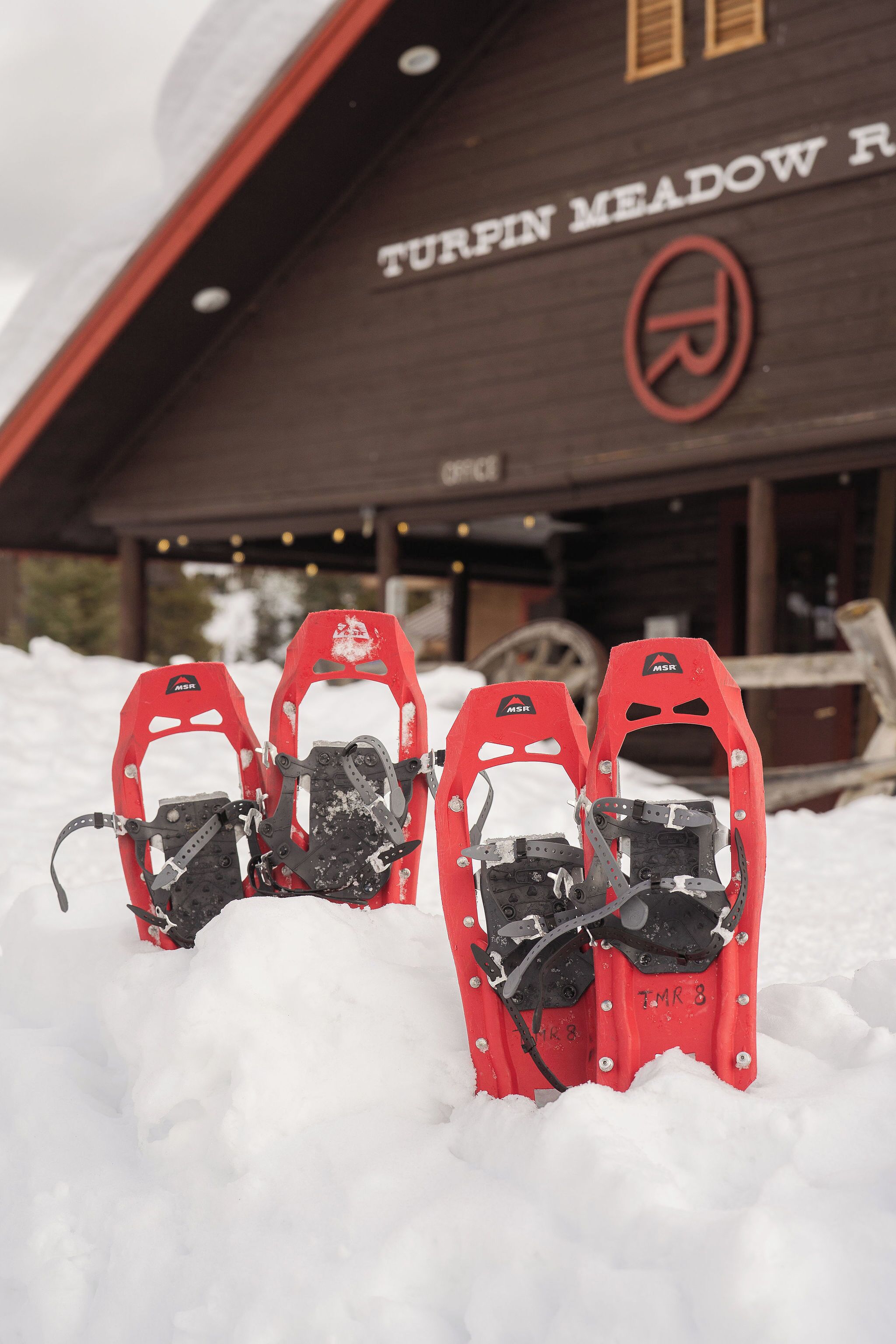 Raquetas de nieve frente a un edificio con letrero que dice 'TURPIN MEADOW R'.
