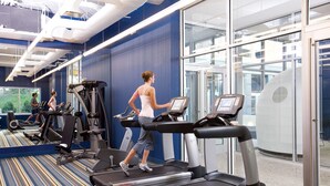 A gym with treadmills, exercise bikes, and a mirrored wall. - Aloft by Marriott Harlem (New York)