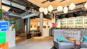 A modern hotel lobby with a bar area, seating, and a reception desk. - Aloft by Marriott Harlem (New York)