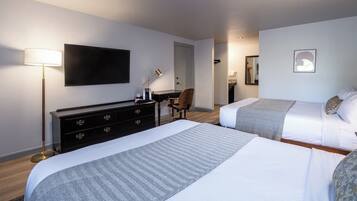 Une chambre d’hôtel avec deux lits, un téléviseur à écran plat, un bureau, une chaise et une lampe.