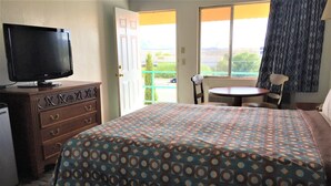 A hotel room with a bed, a TV on a dresser, a small table, and a chair. - Ramblin Rose Motel (Kingman)
