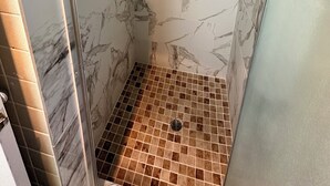 A shower with marble walls and floor tiles. - Ramblin Rose Motel (Kingman)