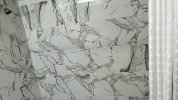 A bathroom with marble tiles, a shower, and a bathtub.