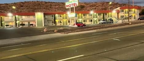 Ein Motel mit Schild, mehreren Parkplätzen und einer Straße davor.