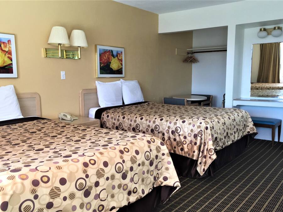 Ett hotellrum med två sängar, ett skrivbord, en stol, en telefon och två väggmonterade lampor.