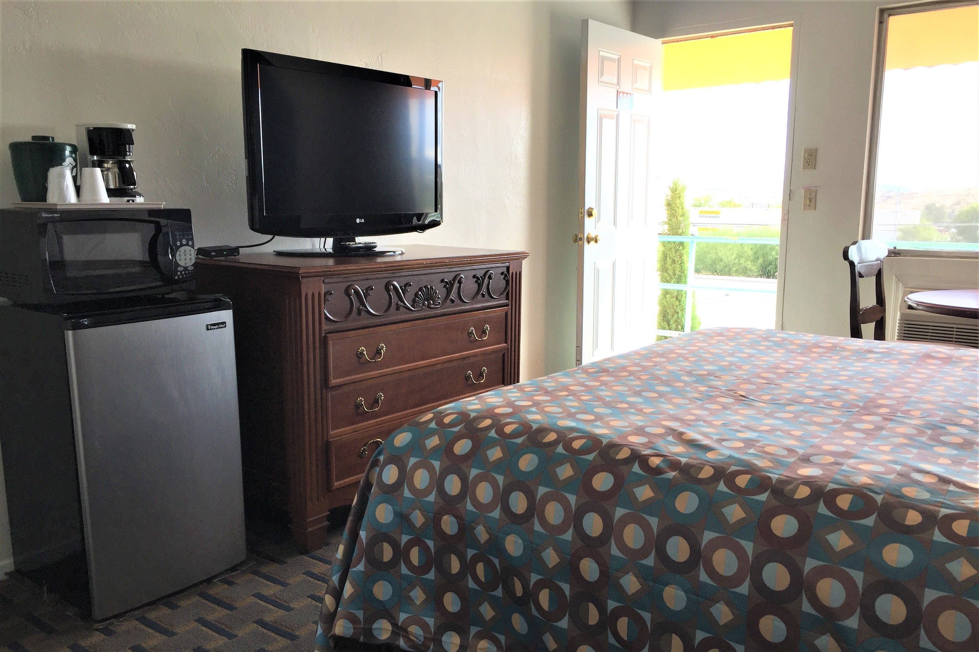Una habitación de hotel con cama, televisión, microondas y refrigerador.