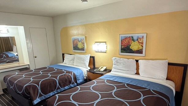 A hotel room with two beds, a desk, a mirror, and two wall-mounted lamps. - Ramblin Rose Motel (Kingman)