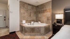 Un baño moderno con una bañera independiente, un tocador con espejo y una mesita de noche con lámpara.