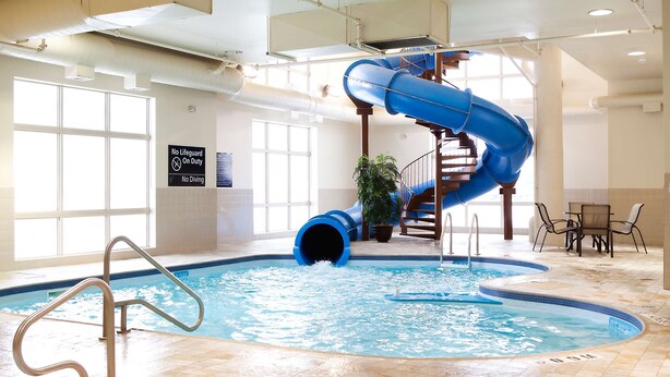 Una piscina interior con un tobogán de agua azul y un letrero que indica ausencia de salvavidas.