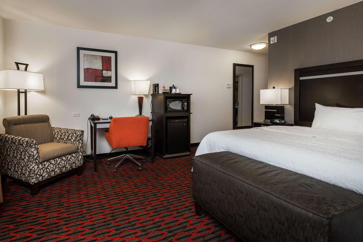 Habitación de hotel con una cama grande, un escritorio con silla, microondas y televisión.