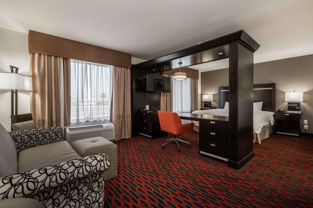 Habitación de hotel con sofá, escritorio, silla, cama y televisión.