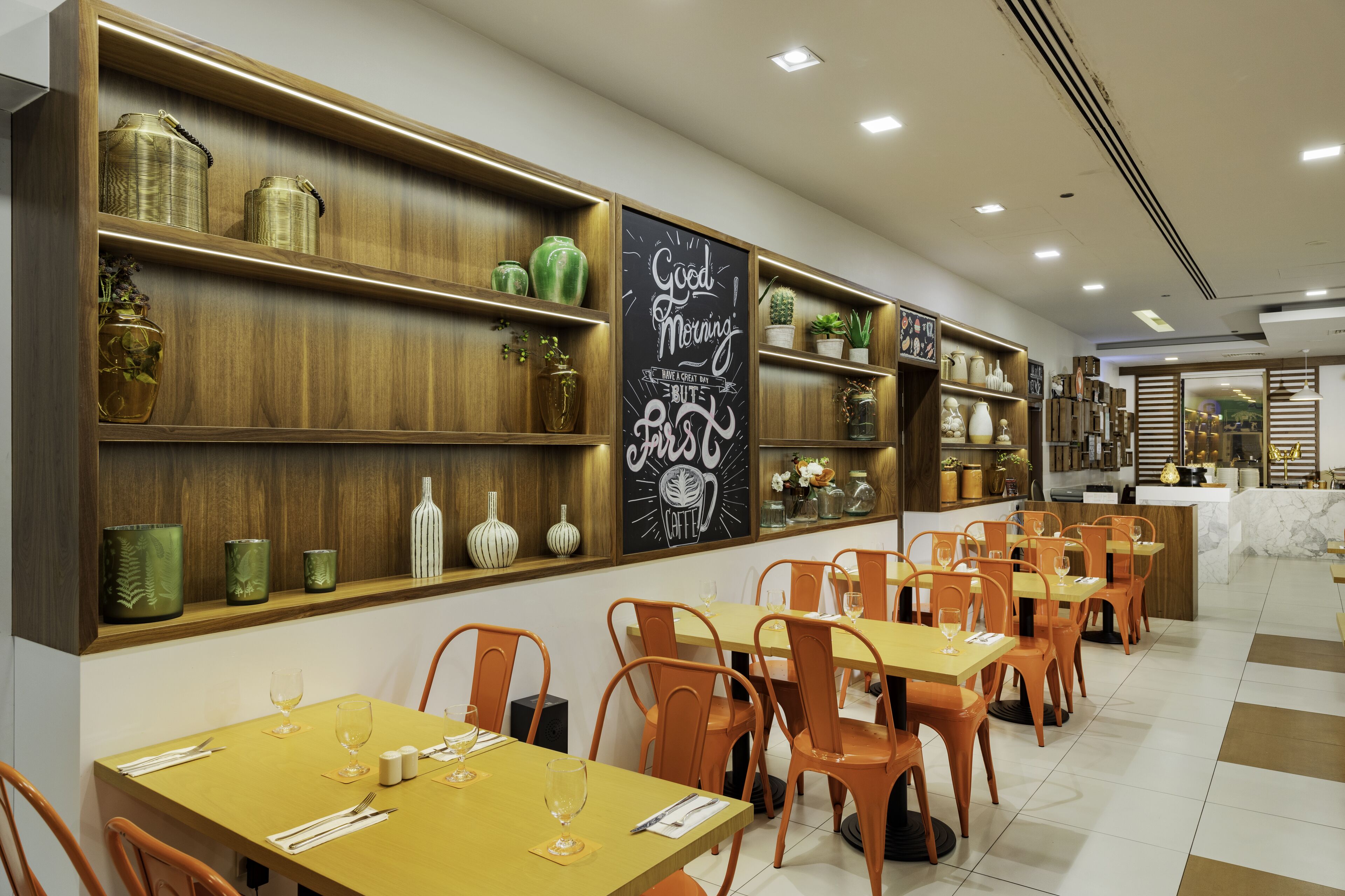 A restaurant interior with wooden shelves, orange chairs, and a chalkboard sign.