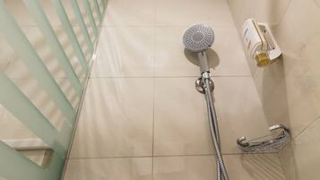 A shower with a handheld showerhead, a wall-mounted showerhead, and a handheld faucet.