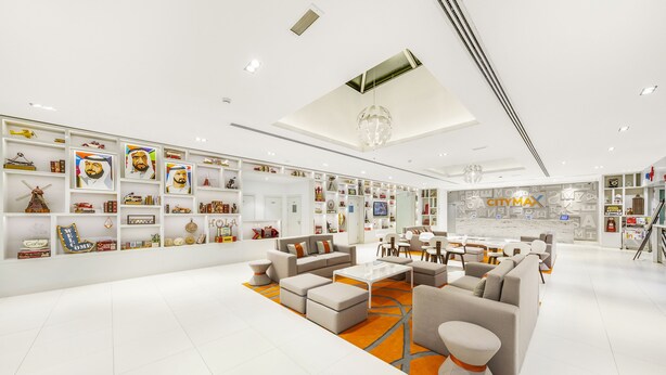 A modern hotel lobby with white walls, a central seating area with sofas and a coffee table, and a large CityMax sign. - Citymax Hotel Al Barsha at the Mall (Dubai)
