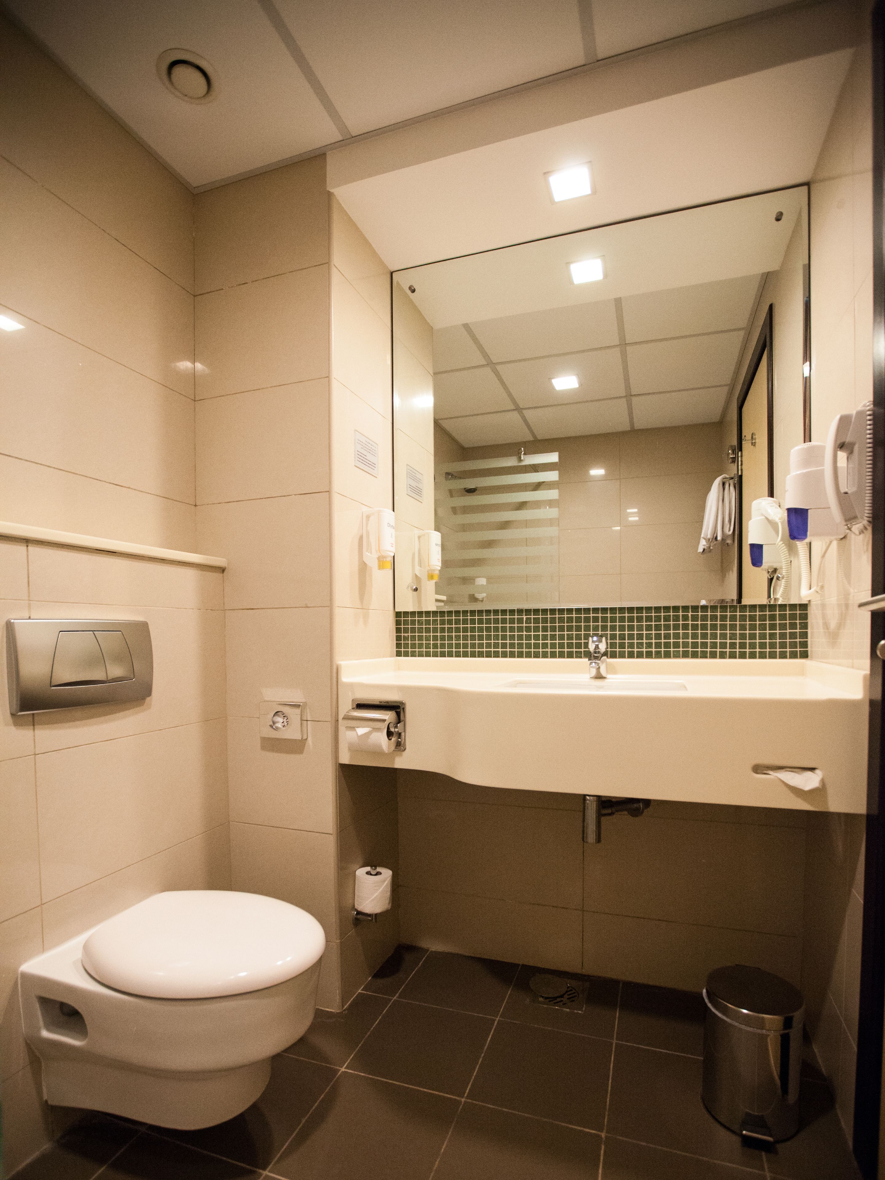 A compact bathroom with a toilet, sink, and mirror.