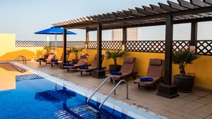 A poolside area with lounge chairs, a pool, and a pergola. - Citymax Hotel Al Barsha at the Mall (Dubai)
