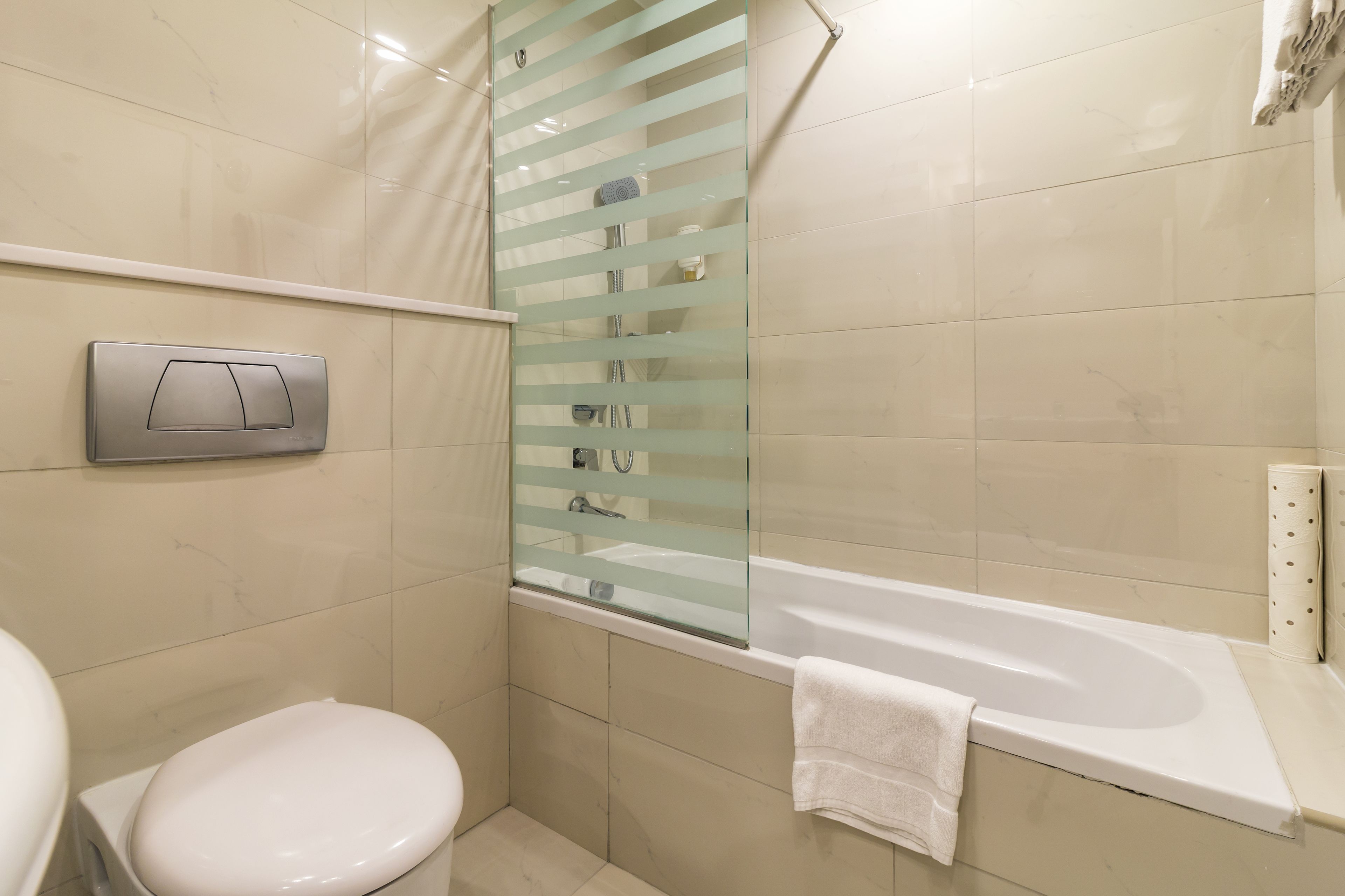 Een moderne badkamer met toilet, een douchecabine van glas en een bad.