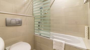 Een moderne badkamer met toilet, een douchecabine van glas en een bad.