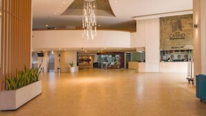 A spacious lobby with a reception desk, a large chandelier, and a wall with the hotel name.