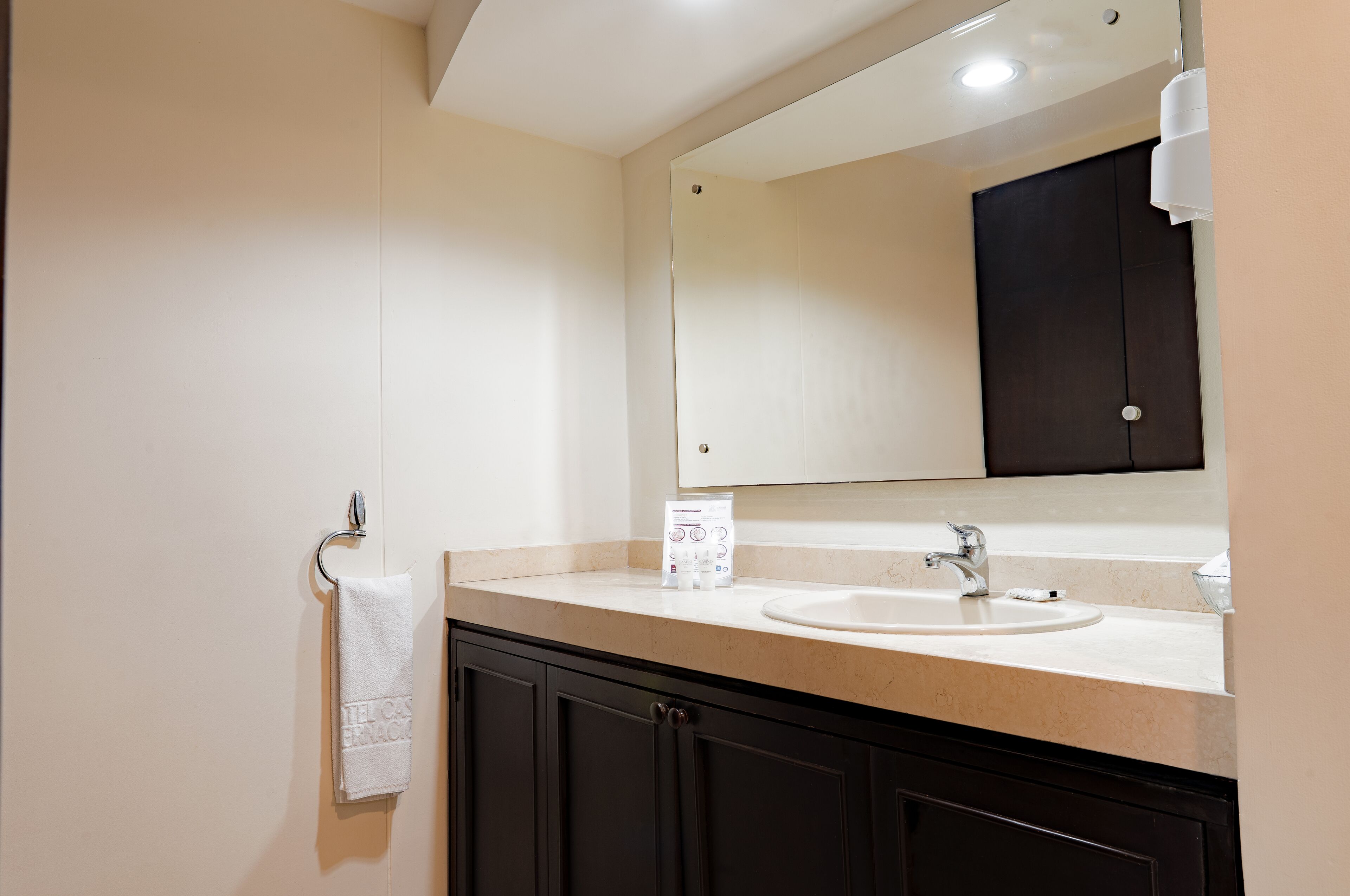 A bathroom with a sink, mirror, towel rack, and dark cabinets.