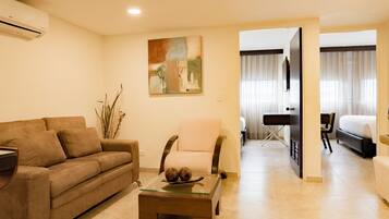 Una sala de estar con sofá, sillón, mesa de centro y un cuadro en la pared.