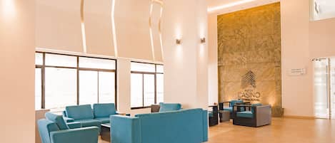 Un hall d’entrée avec des canapés bleus, un comptoir d’accueil et un grand mur orné du logo d’un casino.