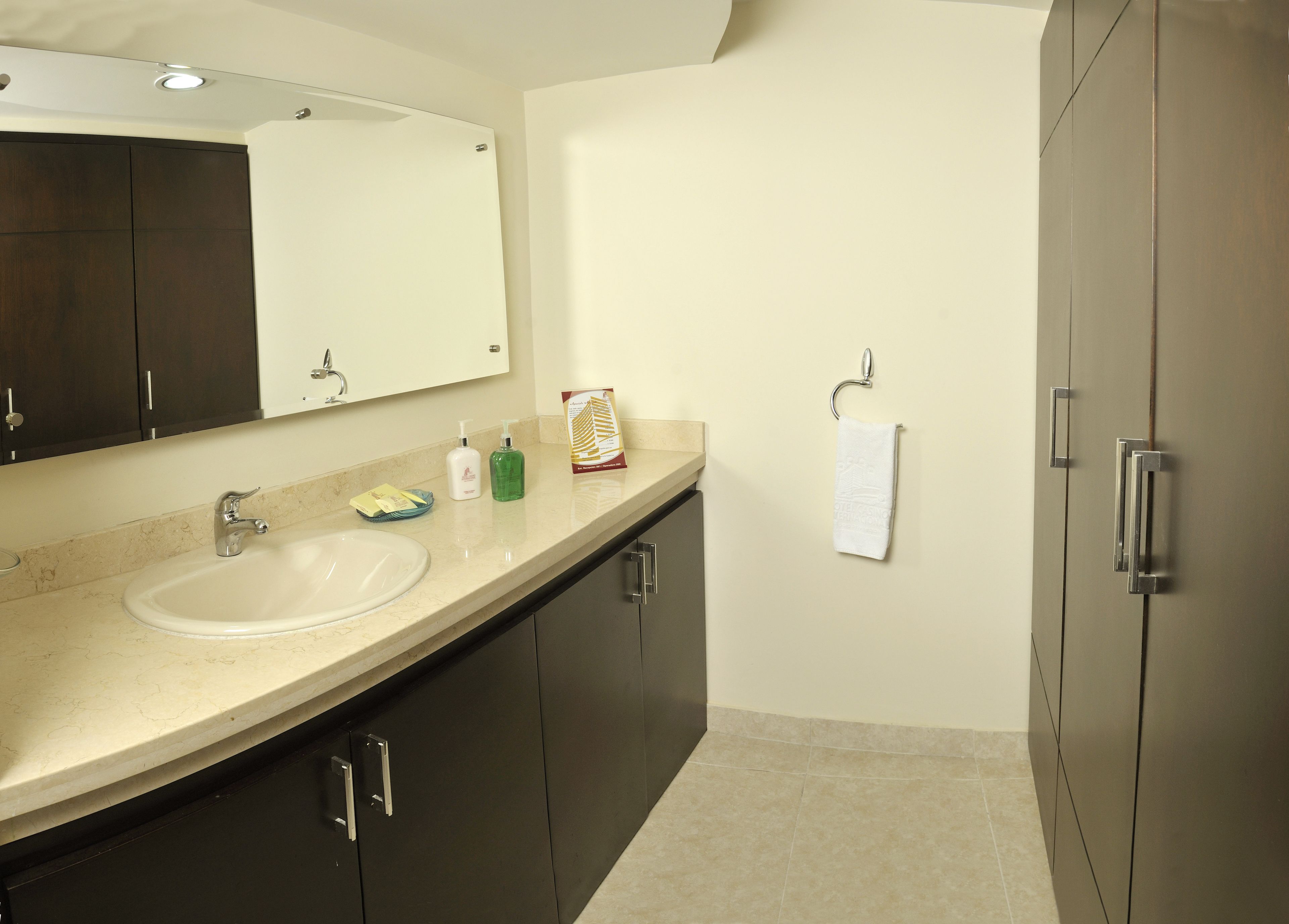 A bathroom with a sink, mirror, dark cabinets, and a towel rack.