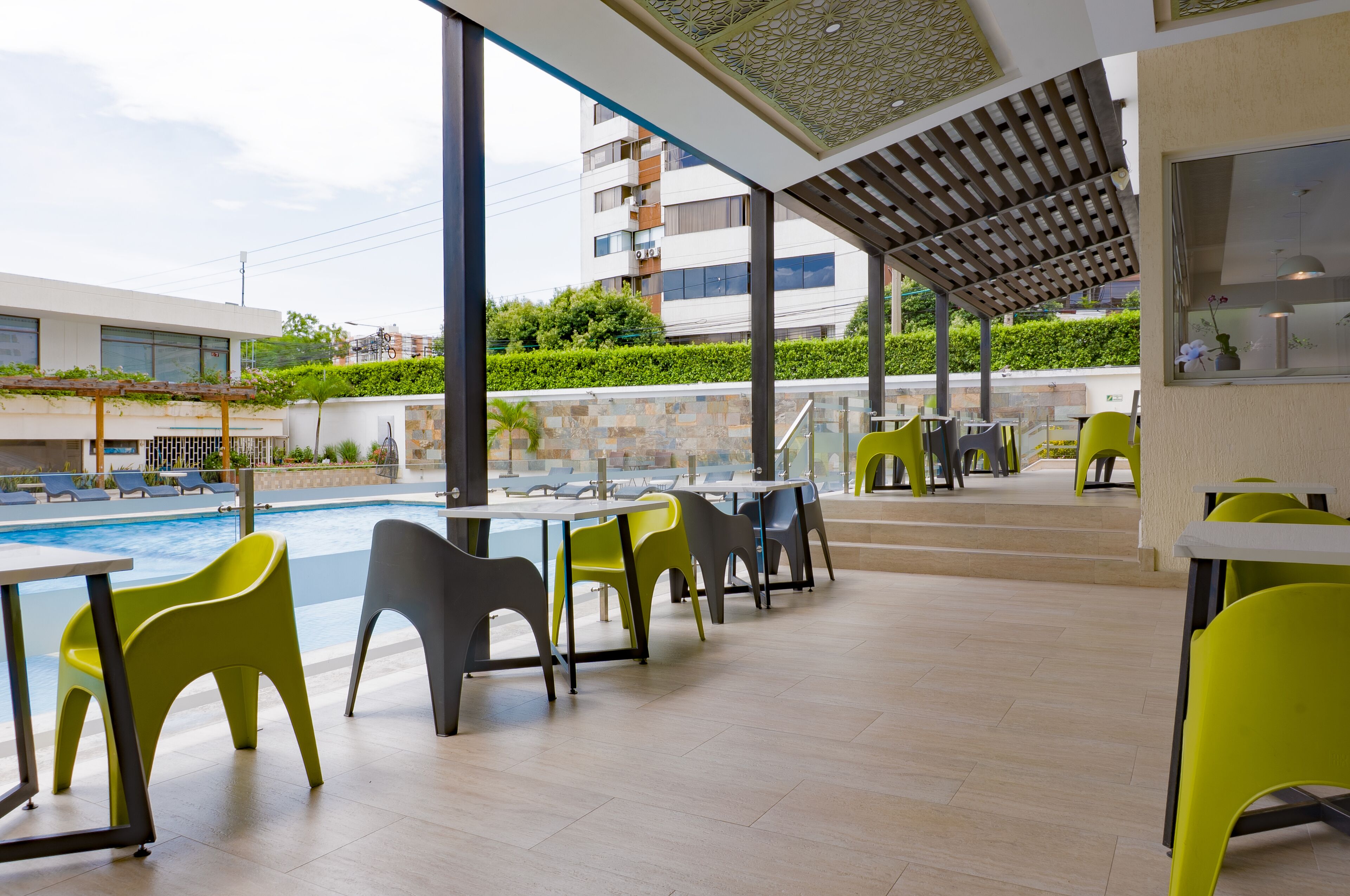 A poolside area with outdoor seating, a view of a building, and a covered patio.