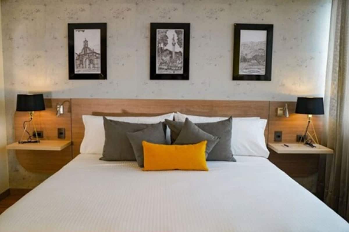 Ein Hotelzimmer mit einem Bett, zwei Nachttischen und drei gerahmten Bildern an der Wand.