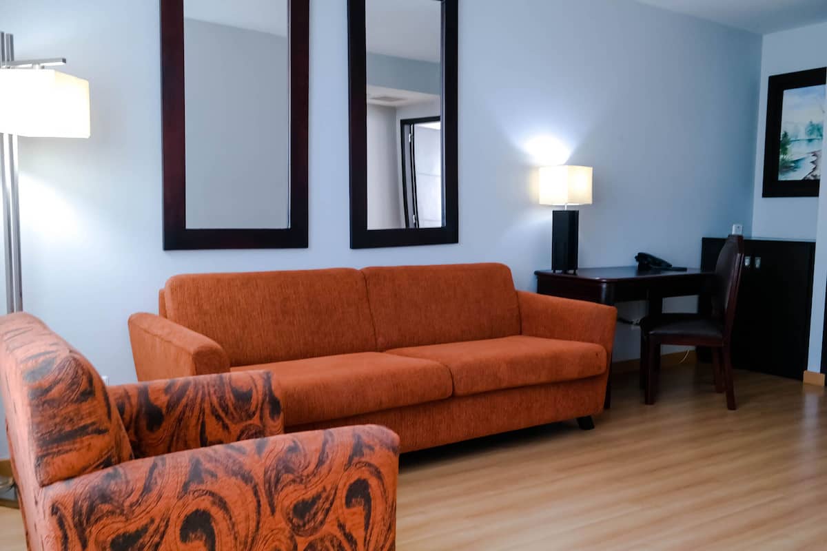 Uma sala de estar com sofá, poltrona e mesa de jantar com cadeiras.