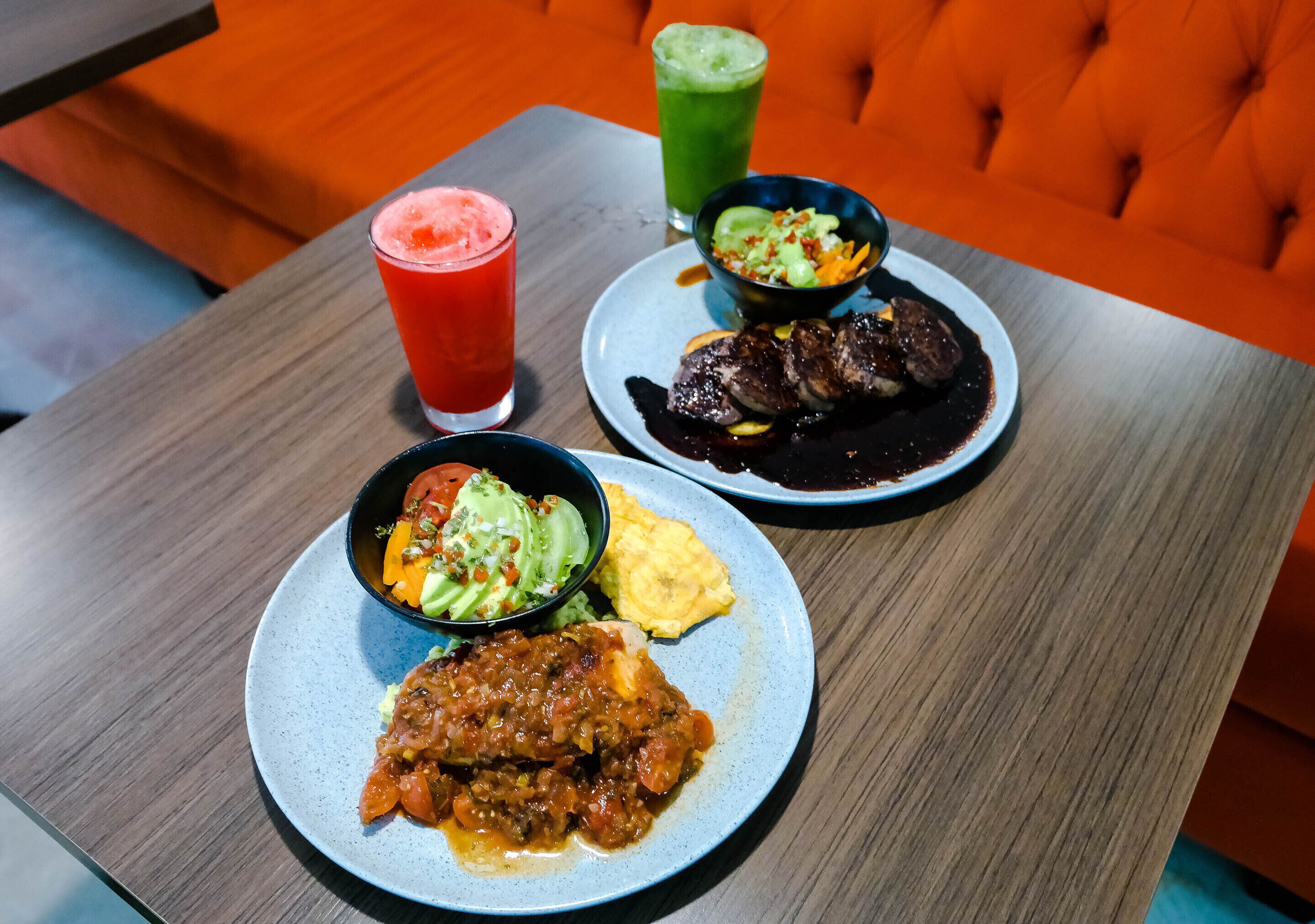 A table with three plates of food, two drinks, and a bowl of salad.