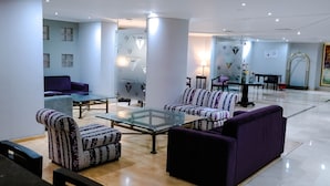 Eine moderne Lobby mit einem violetten Sofa, gemusterten Sesseln und einem Glastisch.