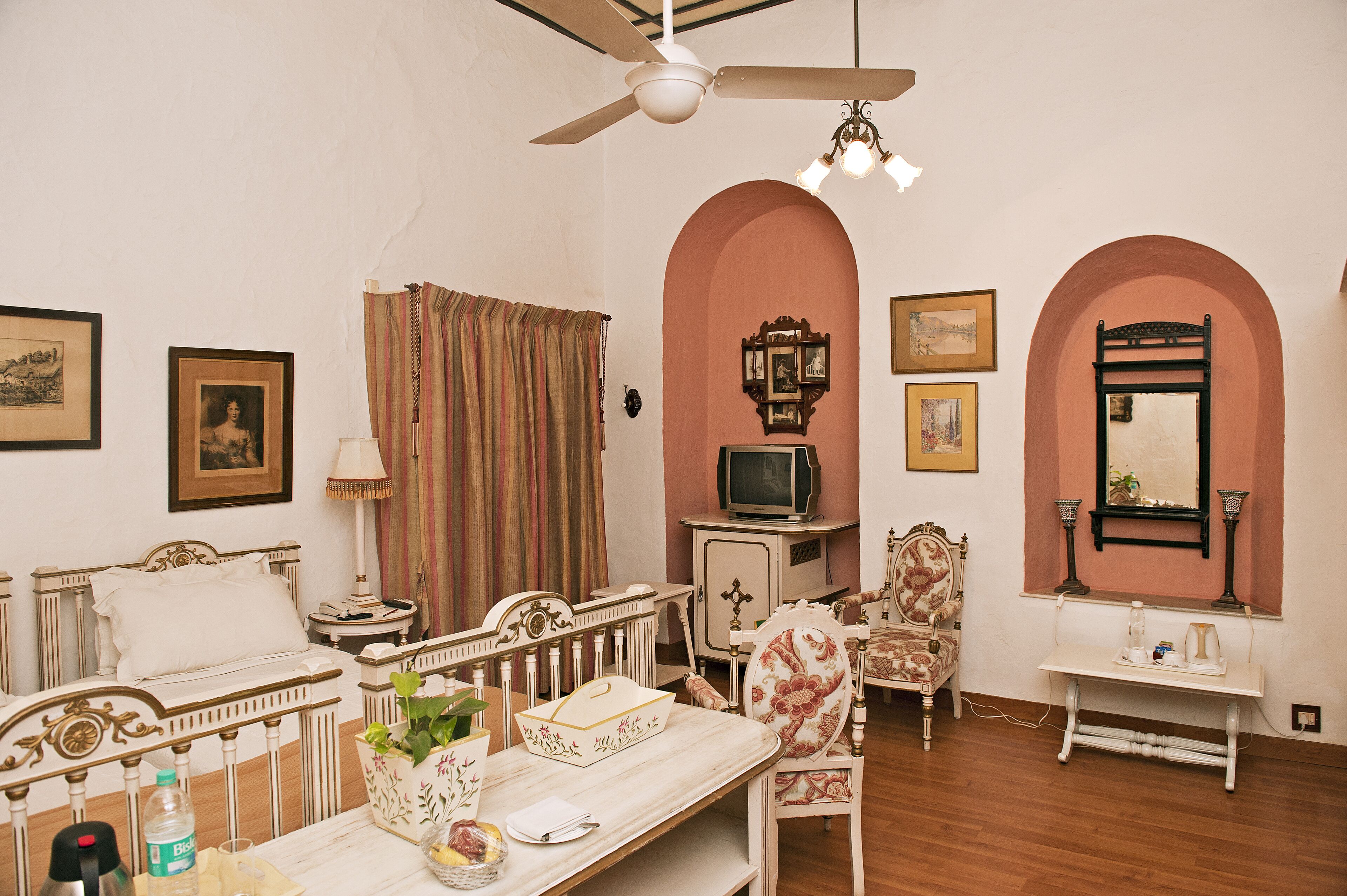 Habitación de hotel con cama, escritorio, silla, televisor y espejo.