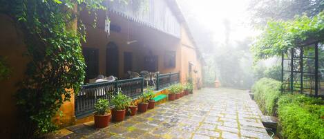 A courtyard with a stone pathway, potted plants, and a building with a balcony.