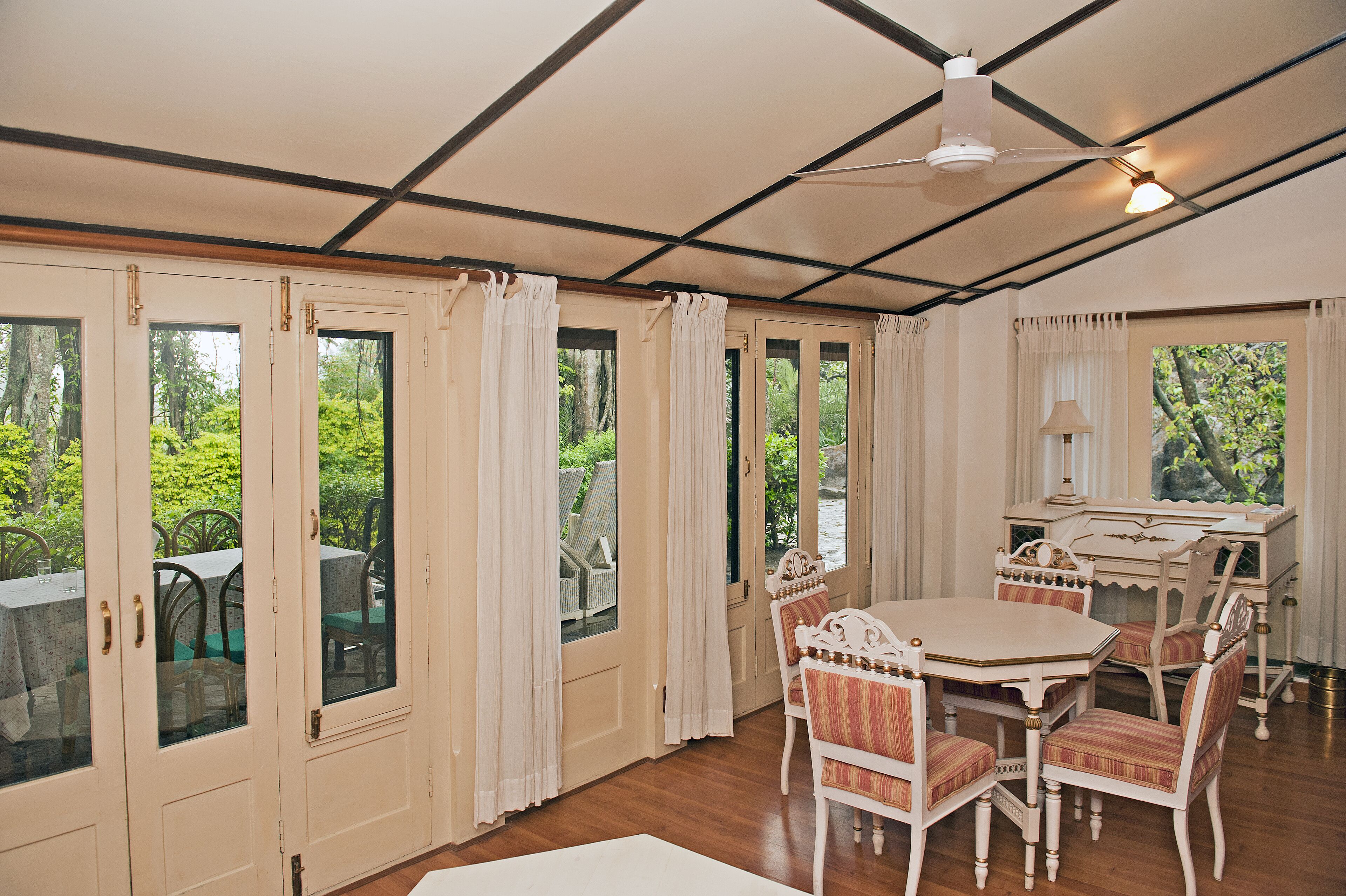 Une pièce comprenant une table à manger, des chaises, un bureau et un ventilateur de plafond.