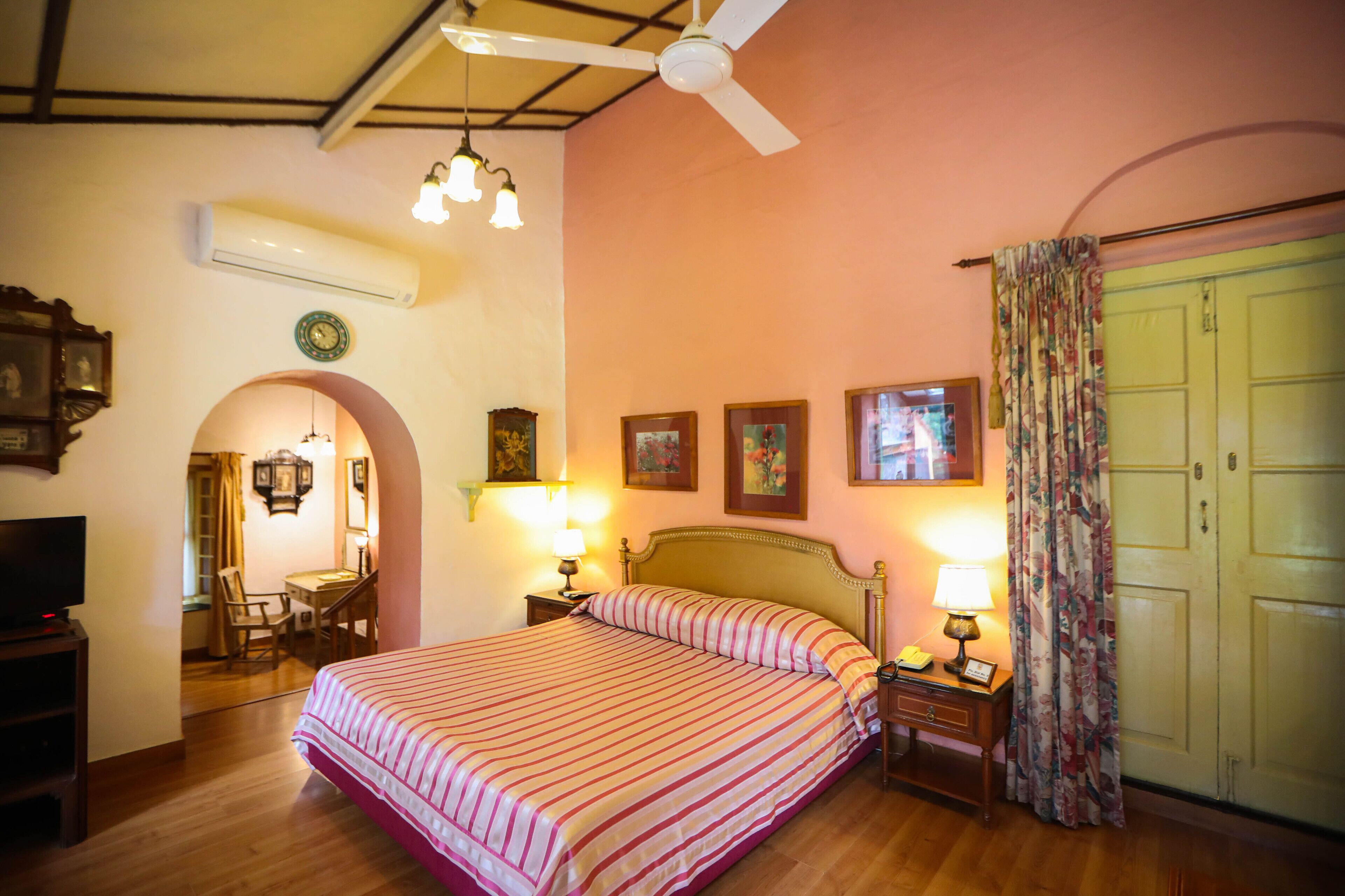 A hotel room with a bed, bedside lamps, a desk, a chair, a television, and a wardrobe.