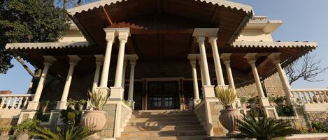 A building with a central entrance, flanked by columns, and a staircase leading up to it.