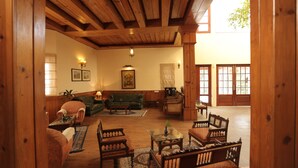 A cozy living room with wooden beams, a green sofa, and a coffee table. - WelcomHeritage Windsor Lodge (Ranikhet)