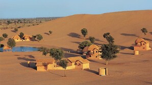 Un paysage désertique parsemé de petites maisons traditionnelles et d’une végétation clairsemée.