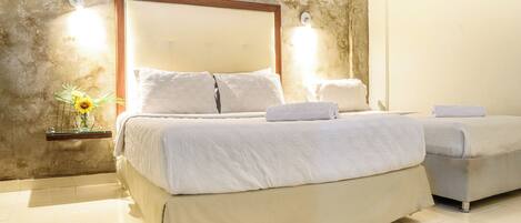 Habitación de hotel con dos camas, un espejo grande y una repisa en la pared con un jarrón.
