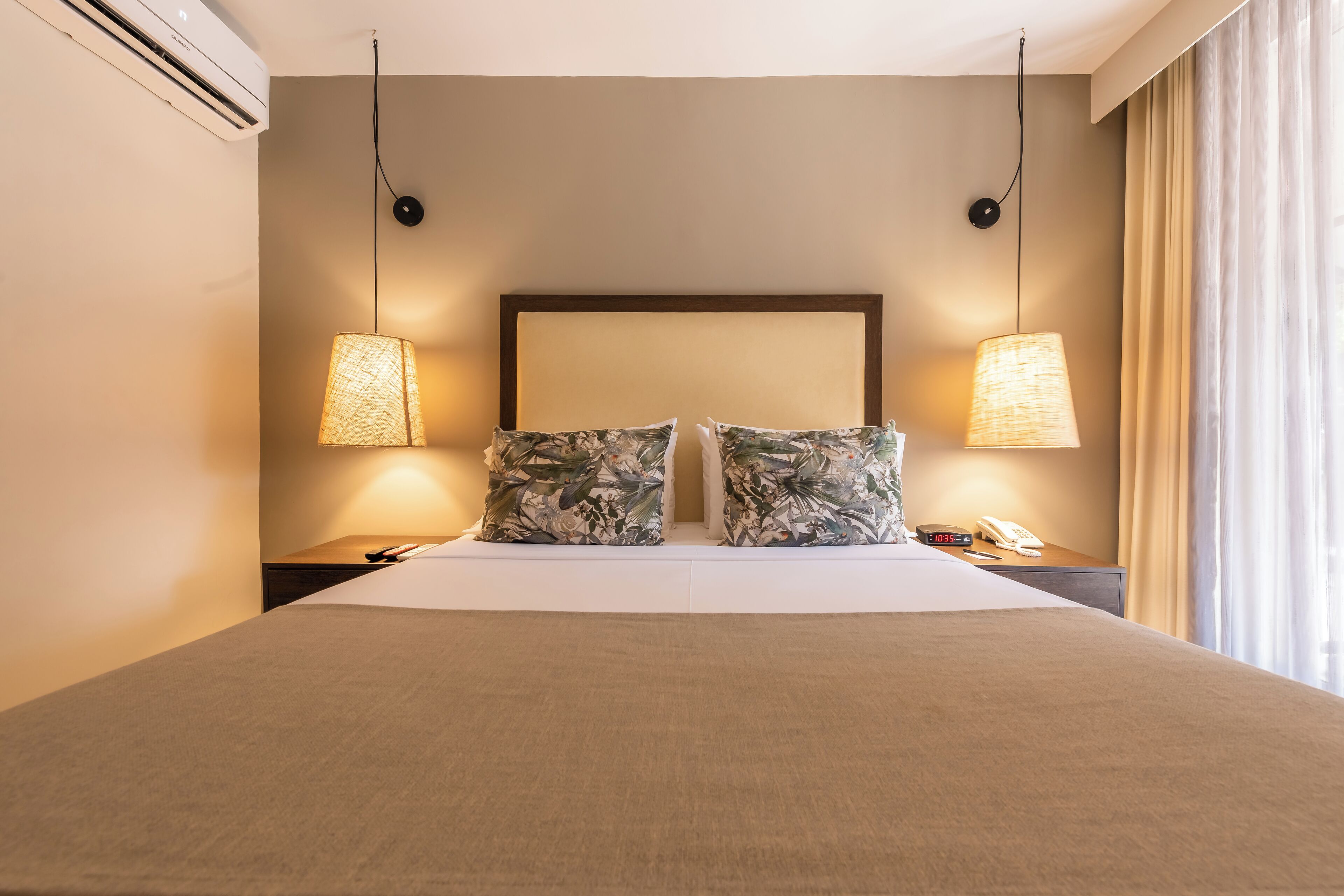 A hotel room with a large bed, two nightstands, a lamp, and a telephone.