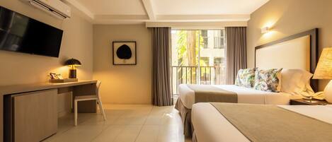 Habitación de hotel con cama, escritorio, silla, televisor y ventana con cortinas.
