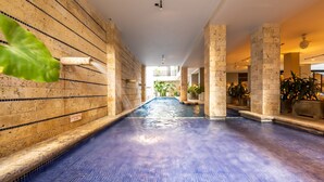 A swimming pool with a blue floor, surrounded by stone walls and columns, with a view of a balcony in the background. - Madisson Boutique Hotel Cartagena (Cartagena)