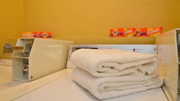 A laundry area with stacked towels, a washing machine, and detergent boxes.