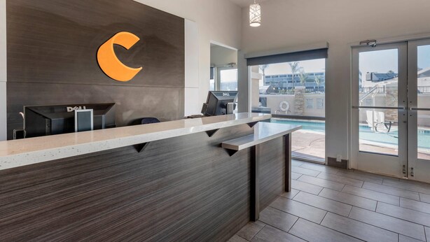 Una recepción con un logotipo grande, una computadora Dell y vista a la piscina.