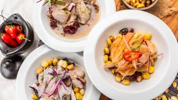 Three bowls of seafood dishes with corn and red onions, and a bowl of corn kernels.