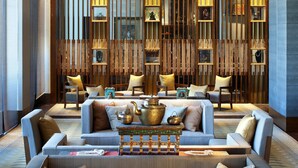 A modern lobby with sofas, a coffee table, and a decorative wooden wall.