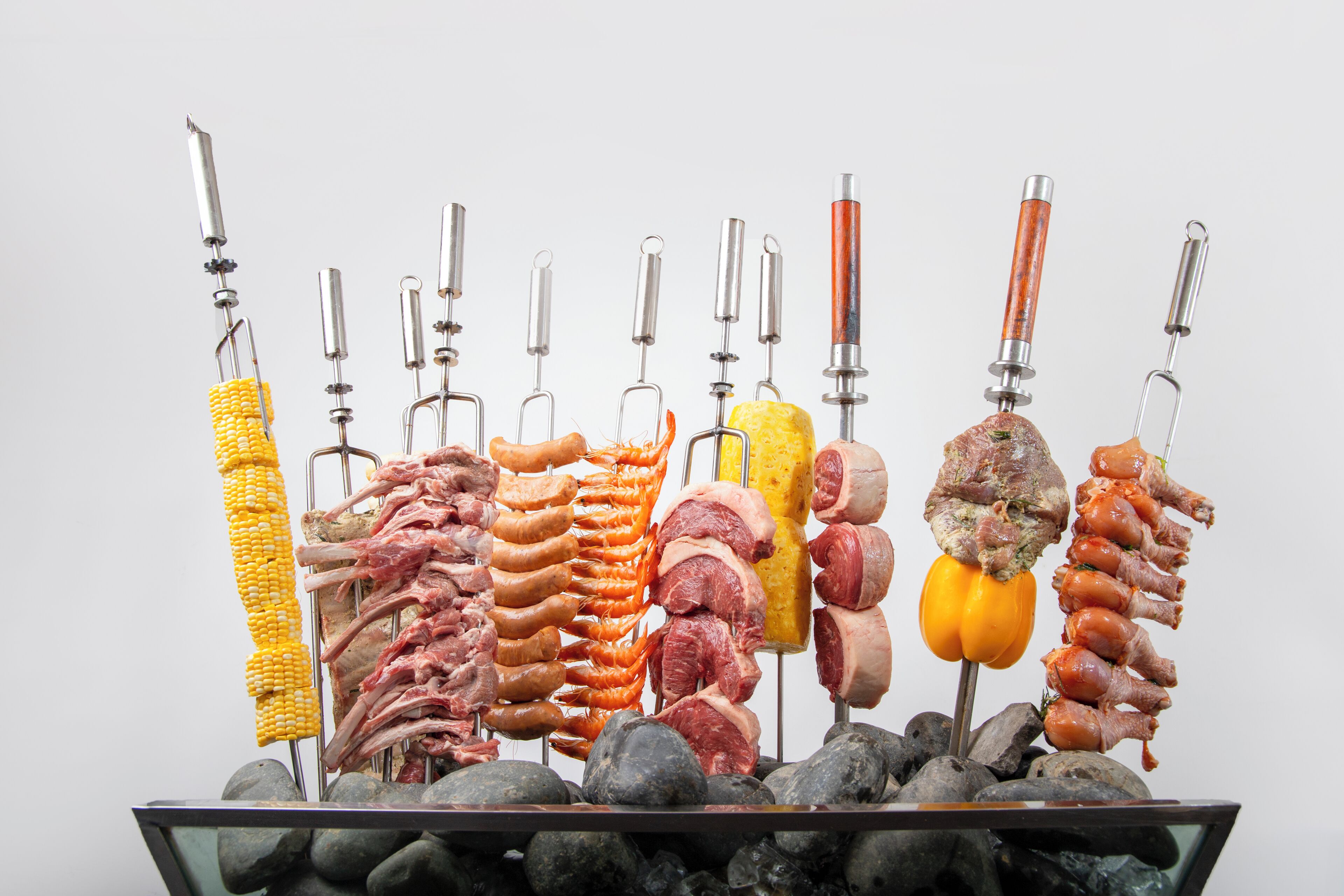 Diversas carnes y verduras en una parrilla giratoria vertical.