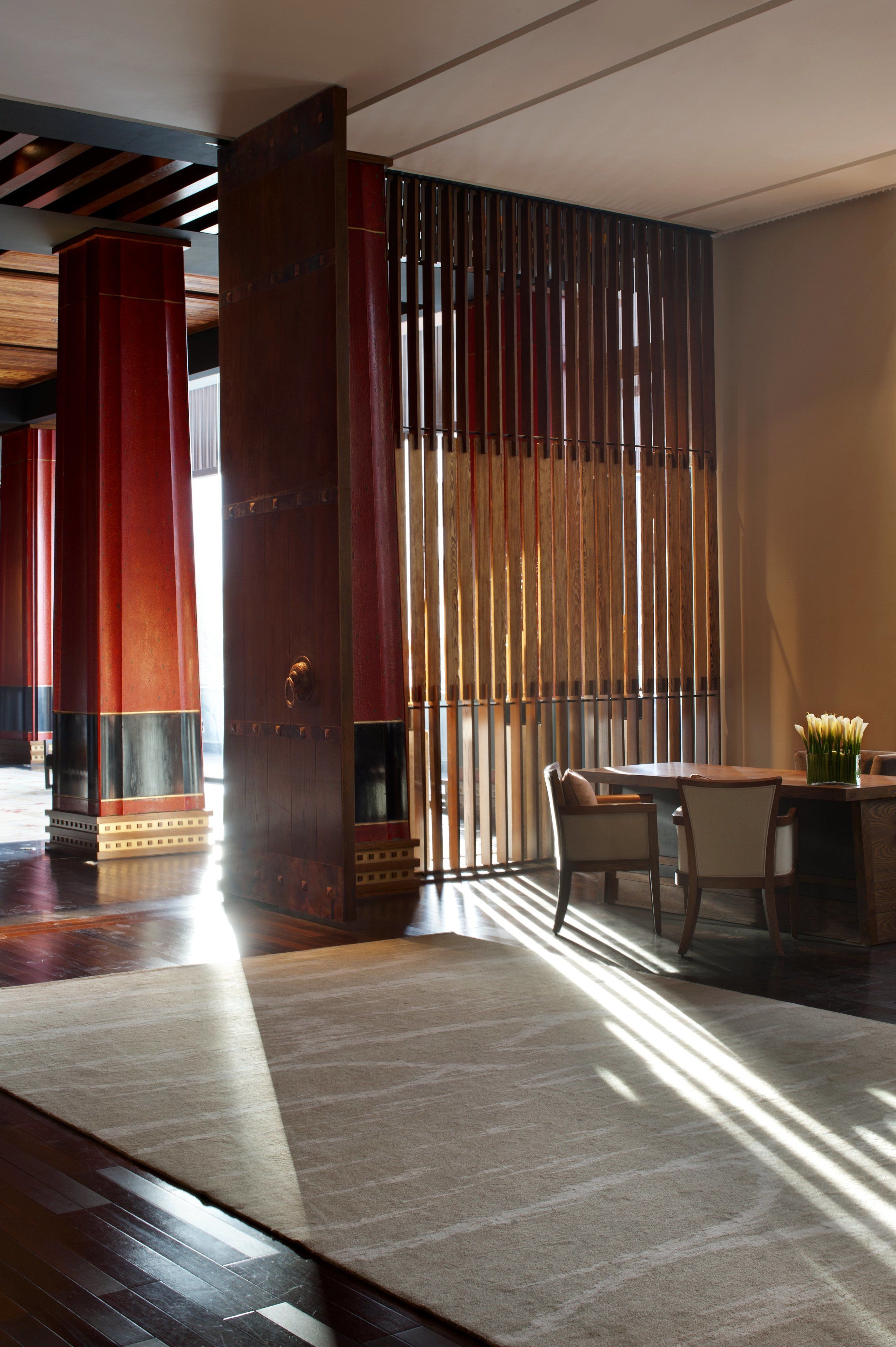 A room with a large window, a wooden floor, and a table with chairs.