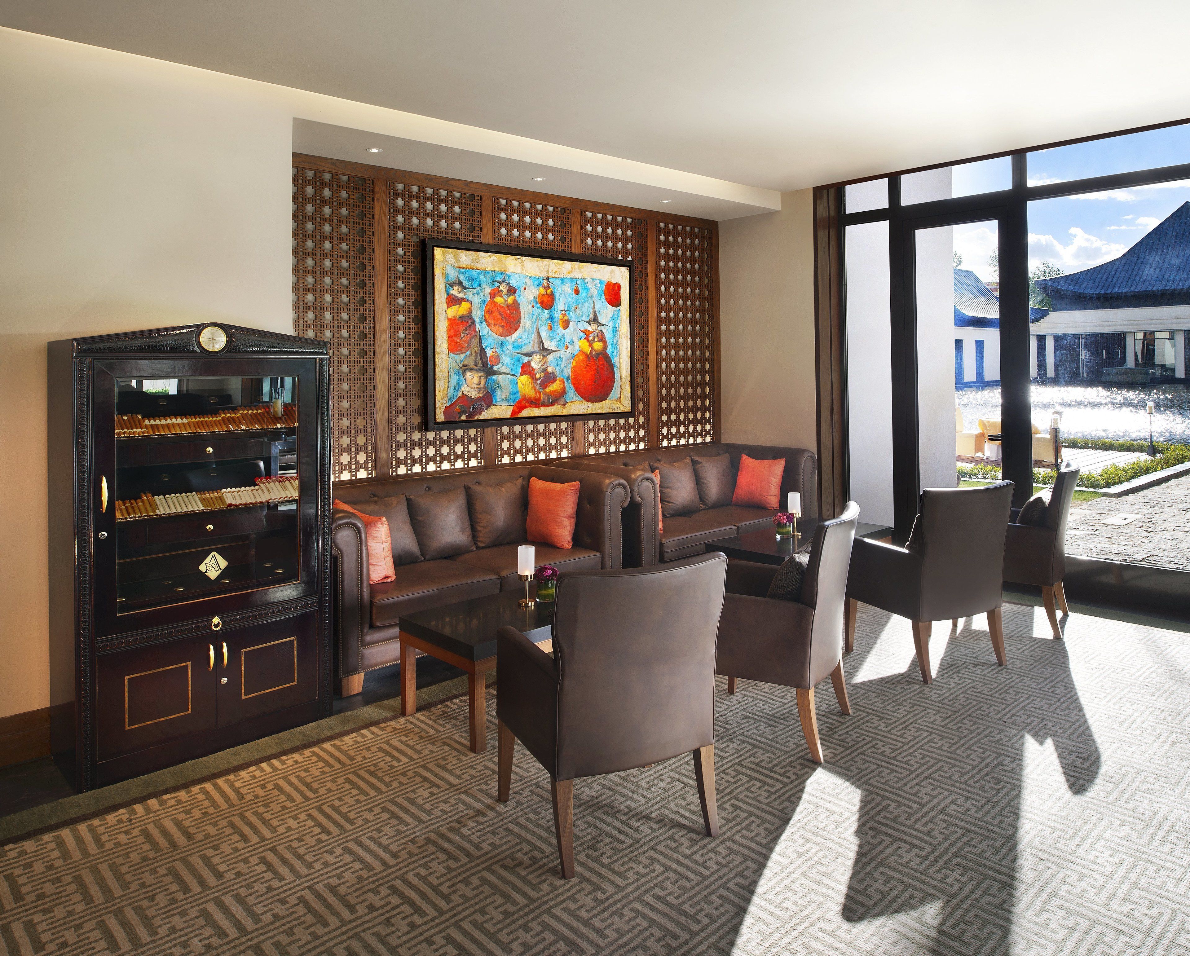 A modern hotel lobby with a leather sofa, a glass cabinet, and a large window offering a view of the outside.